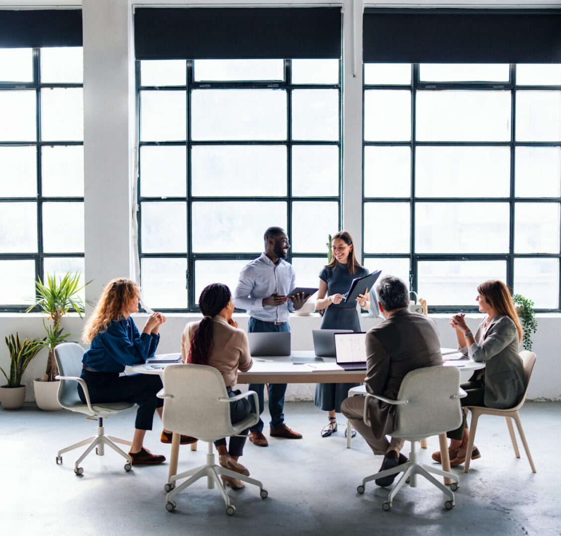 A diverse group of professionals collaborating in a modern office space, engaging in a productive team discussion to align project goals and ideas. Bright setting emphasizes team cooperation and innovative workplace spirit.